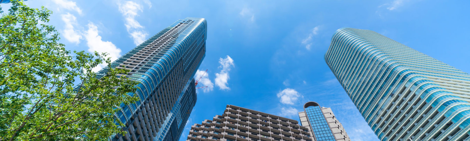 青空を背景に高層ビルがそびえる都市風景（会社概要ページへのリンク）